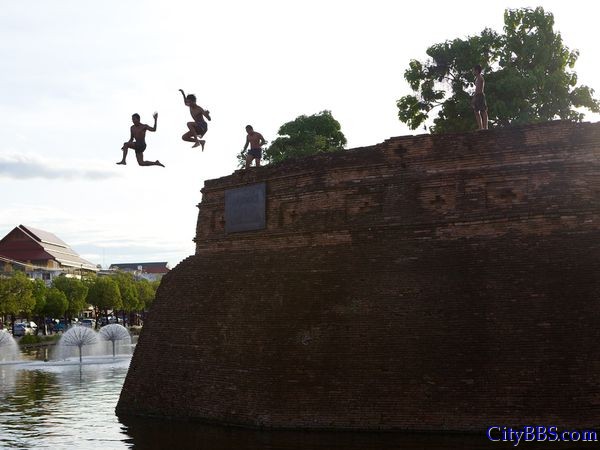 清迈的夏日无忧无虑的男孩飞跃清迈老城墙边上的护城河之上。