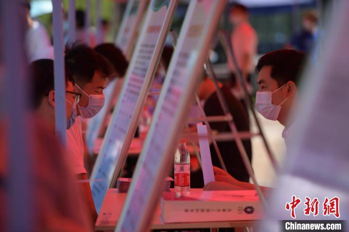 大学生在招聘单位展台前咨询