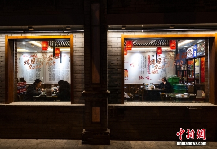 一些市民在北京市东直门内大街的“簋街”的餐厅享用晚餐
