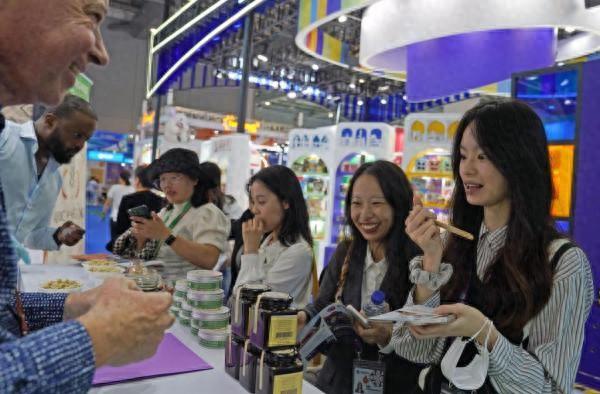 在第六届进博会食品及农产品展区，参观者试吃贝宁蜂蜜