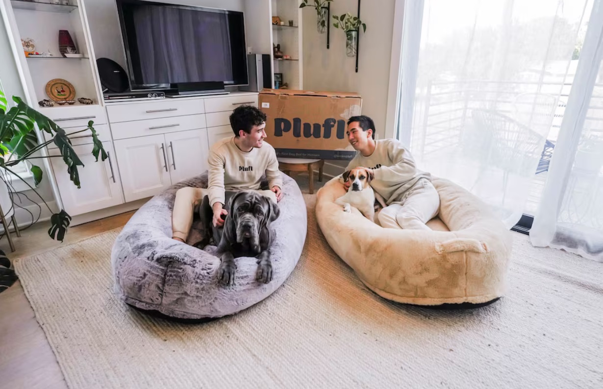 Plufl创始人Noah Silverman和Yuki Kinoshita在一家商店里与他们在中国制造的“人狗床”合影 ...